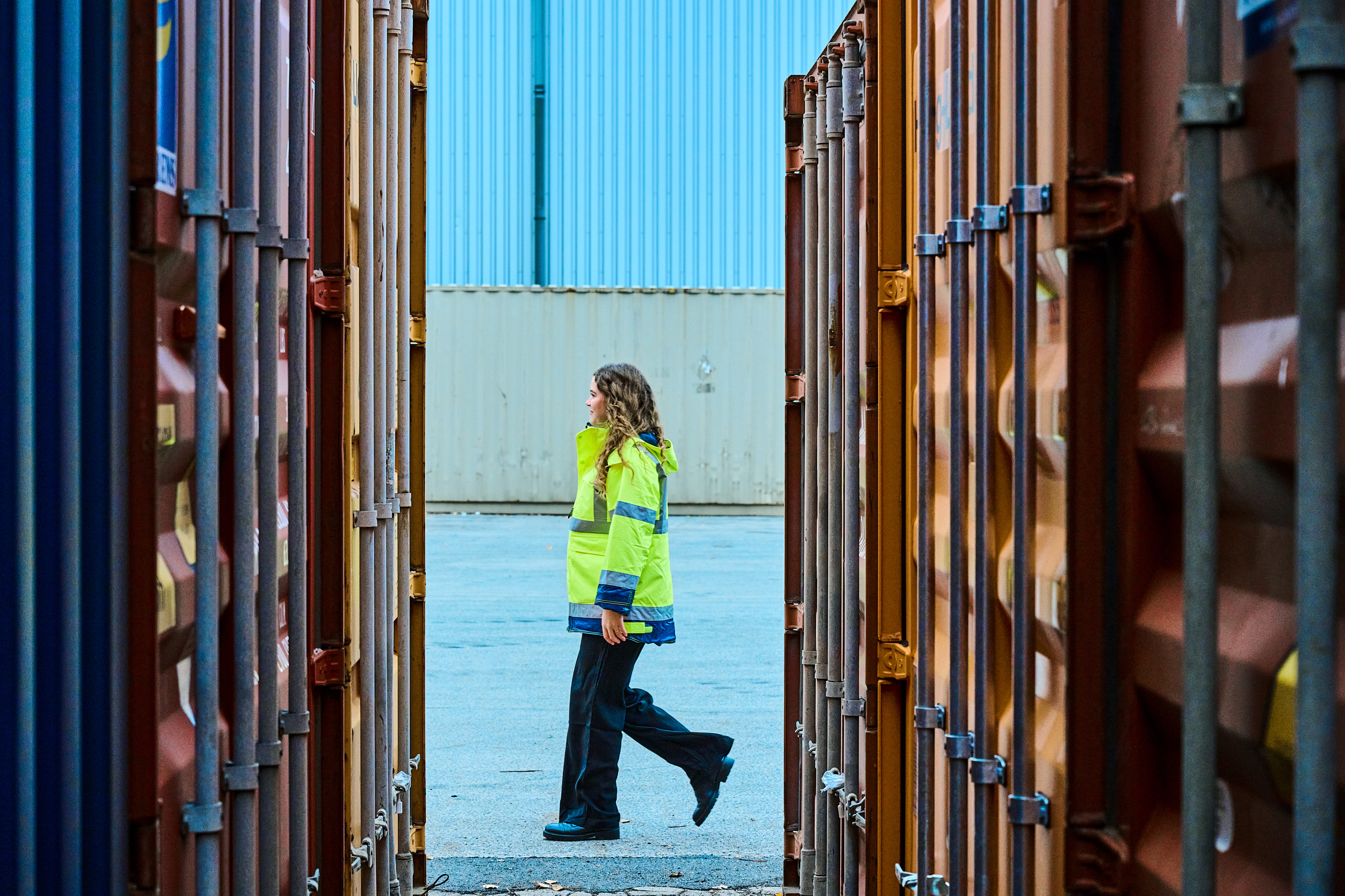 Mujer entre contenedores marítimos. Logística.